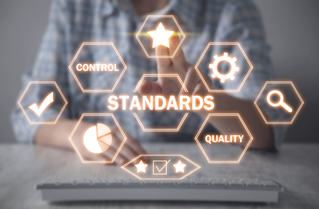 A person touches a glowing virtual screen with hexagons labelled “Standards,” “Control,” “Quality,” and Staff Hub icons, symbolising business quality control and streamlined standards management.