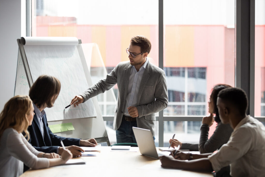 A team meeting with a male presenter standing at a flipchat board.