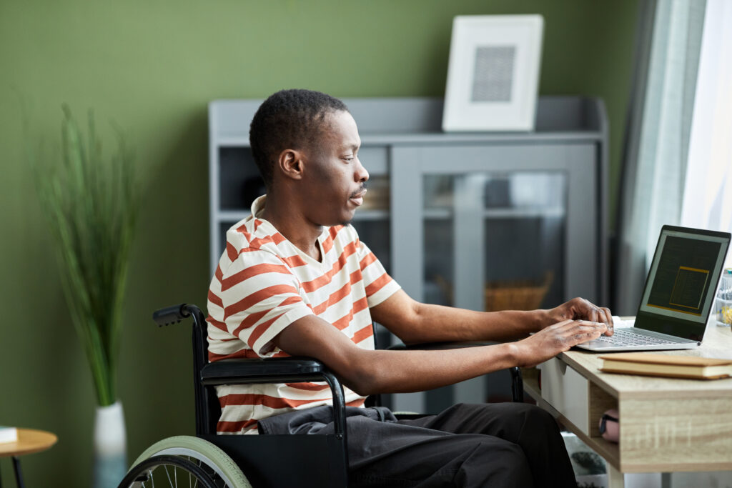 African American man in a wheelchair at a desk using laptop